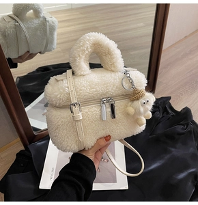 Detail of white faux shearling handbag with silver hardware and a cute doll charm