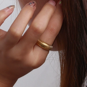 Close-up of a finger wearing a gold-plated stainless steel ring with ribbed texture design
