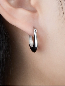 Close-up of minimalist silver U-shaped hoop earrings worn on ear with high polish finish