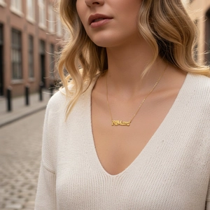 Close-up of a 18K gold plated I love Mama pendant necklace worn by a woman
