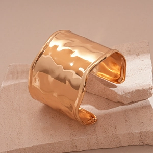 Detailed macro view of the irregular hammered texture on the gold wide open cuff bracelet