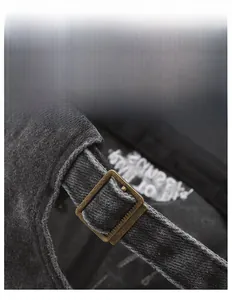 Detail of adjustable brass metal buckle on vintage washed dark grey baseball cap