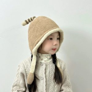 Detail of kids knit hat with penguin badge, striped tail and warm ear flaps in khaki