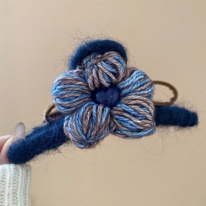 Détail macro d'une pince à cheveux fleur en laine tricotée avec texture bleue et perle
