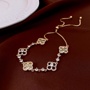 Detail of four-leaf clover bracelet in gold with white shell inlay and zircon stones