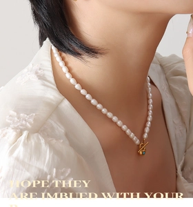 Detail of freshwater pearl necklace with gold heart pendant and blue gemstone on a model