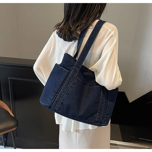 Detail of dark blue denim tote bag with large front pocket and wide shoulder straps
