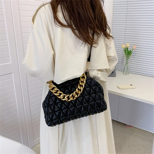 Black quilted rhombic shoulder bag with a gold chunky chain strap shown on model