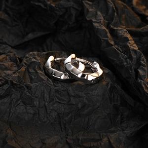 Close-up of silver hoop earrings with irregular wave texture on black background