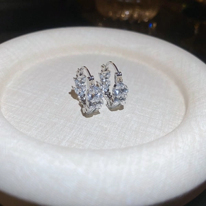 Macro detail of silver U-shaped leaf earrings with sparkling marquise zircon inlay