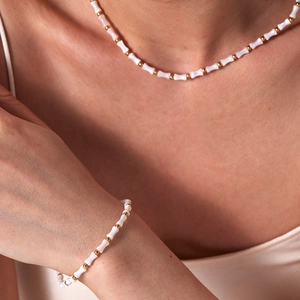 Detailed view of bamboo style shell bead necklace and bracelet set on a female model