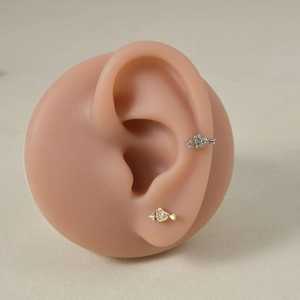 Macro view of heart-shaped arrow earrings with pavé zircons on silicone ear model