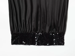 Close-up of black satin dress hem featuring shimmering sequin splicing details