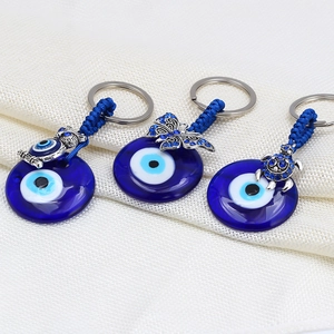 Detail of blue evil eye glass keychains with silver owl, turtle and butterfly charms