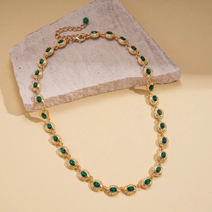 Detail of vintage gold necklace featuring oval green gemstones and lobster clasp closure