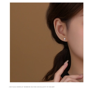 Close-up of a minimalist s925 silver curved stud earring with a single zircon stone