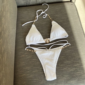Detailed close-up of white seersucker bikini with gold heart crystal buckle and metal chains