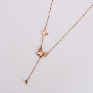 Gros plan détaillé du collier pendentif papillon en or rose avec pompons en métal