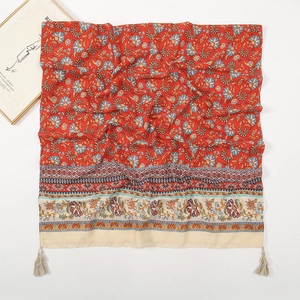 Detailed close-up of a red ethnic paisley print scarf with light gray fringe tassels