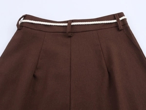 Detail of dark brown straight trousers with white braided rope belt and pleated waist