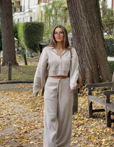 Detail of oat beige knit tracksuit featuring a zip-up hoodie and drawstring wide-leg pants
