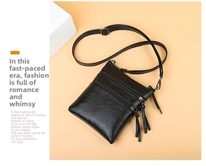 Detailed view of a stylish black soft leather crossbody phone bag with decorative tassels.