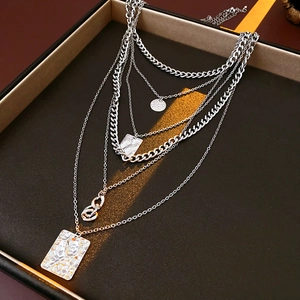 Detail view of silver layered square necklaces with hammered metal pendants in a gift box