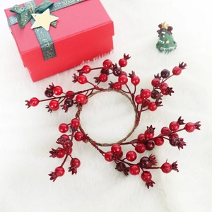 Christmas candle ring with red berries and faux pomegranates on white fur background