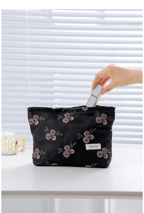 Detailed close-up of vintage black jacquard makeup bag with berry leaf embroidery