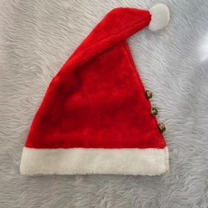 Detail of red plush Christmas hat featuring three copper bells on a soft white fur background