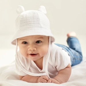 Detailed close-up of a white cotton baby sun hat with cute ears and chin straps
