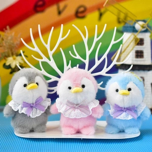 Three cute colorful plush penguin pendants with lace collars and purple bows on display.