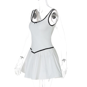 Détail de robe courte blanche avec passepoil noir contrasté et nœuds sur un mannequin de couture