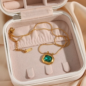 Macro view of 18K gold plated lock pendant necklace with emerald zircon in jewelry box