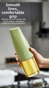 Ergonomic green glass oil bottle with gravity lid shown held in a modern kitchen scene