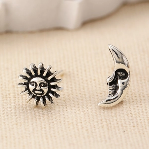 Macro shot of silver sun and moon stud earrings with vintage anthropomorphic faces
