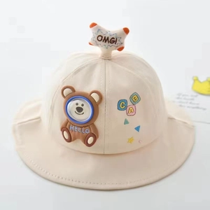 Close-up of beige baby bucket hat featuring brown bear patch and ABC letter embroidery