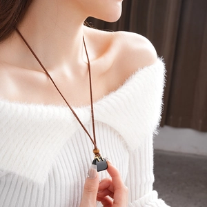 Close-up of a model wearing the black pendant necklace with wooden bead and leather cord