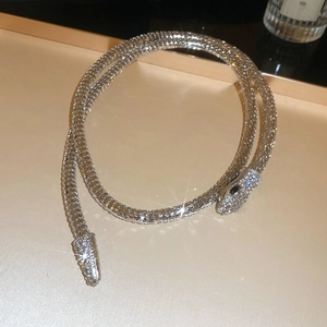 Macro shot of silver snake necklace with sparkling diamonds and black gemstone eyes