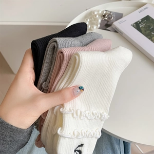 Close-up of four-color ruffled ankle socks with ribbed texture and bow embroidery detail