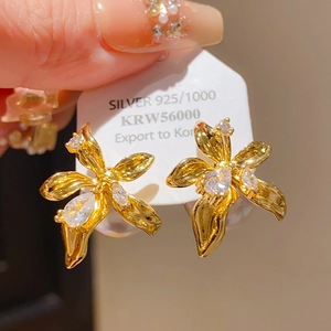 Gros plan détaillé de boucles d'oreilles fleur dorée avec cristaux et poinçon Argent 925