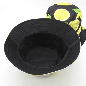Reversible bucket hat featuring black solid side and yellow lemon fruit print on cotton fabric