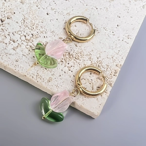 Macro detail of tulip pendant earrings with pink glass petals and 18K gold hoops