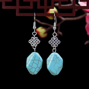 Detailed shot of ethnic turquoise earrings with silver Chinese knot and floral accents