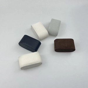Five velvet watch pillows in assorted colors including black and beige on white background