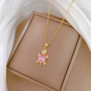 Macro shot of a gold turtle pendant with a pink oval zircon and white crystal accents