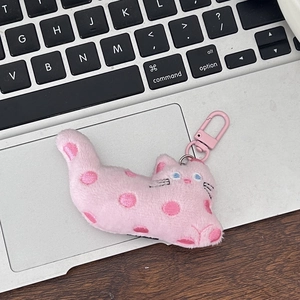 Close-up of pink polka dot plush cat charm on a laptop with pink metal clasp detail