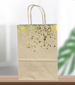 Detail of kraft paper gift bag with gold foil heart pattern and twisted paper handles