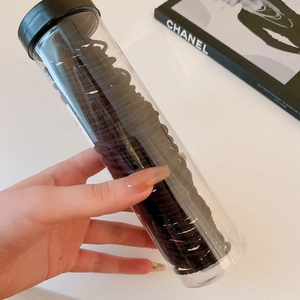 Detail of black elastic hair ties set in a clear plastic storage tube with screw cap