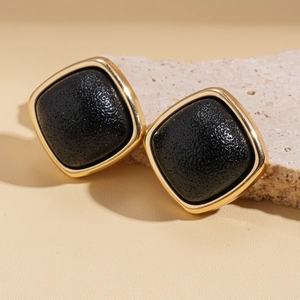 Detail of square vintage leather earrings with black texture and gold metallic frame